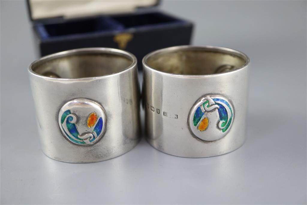 A cased pair of Edwardian Art Nouveau silver and enamel napkin rings, by William Hair Haseler,